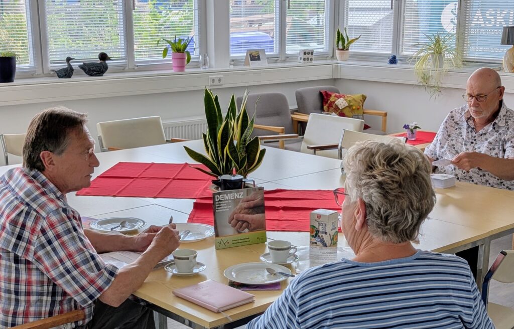 Herr Stahl, Frau Ribbe und Herr Ribbe sitzen am Tisch in dem Gruppenraum der Alzheimer Gesellschaft Landkreis Goslar.